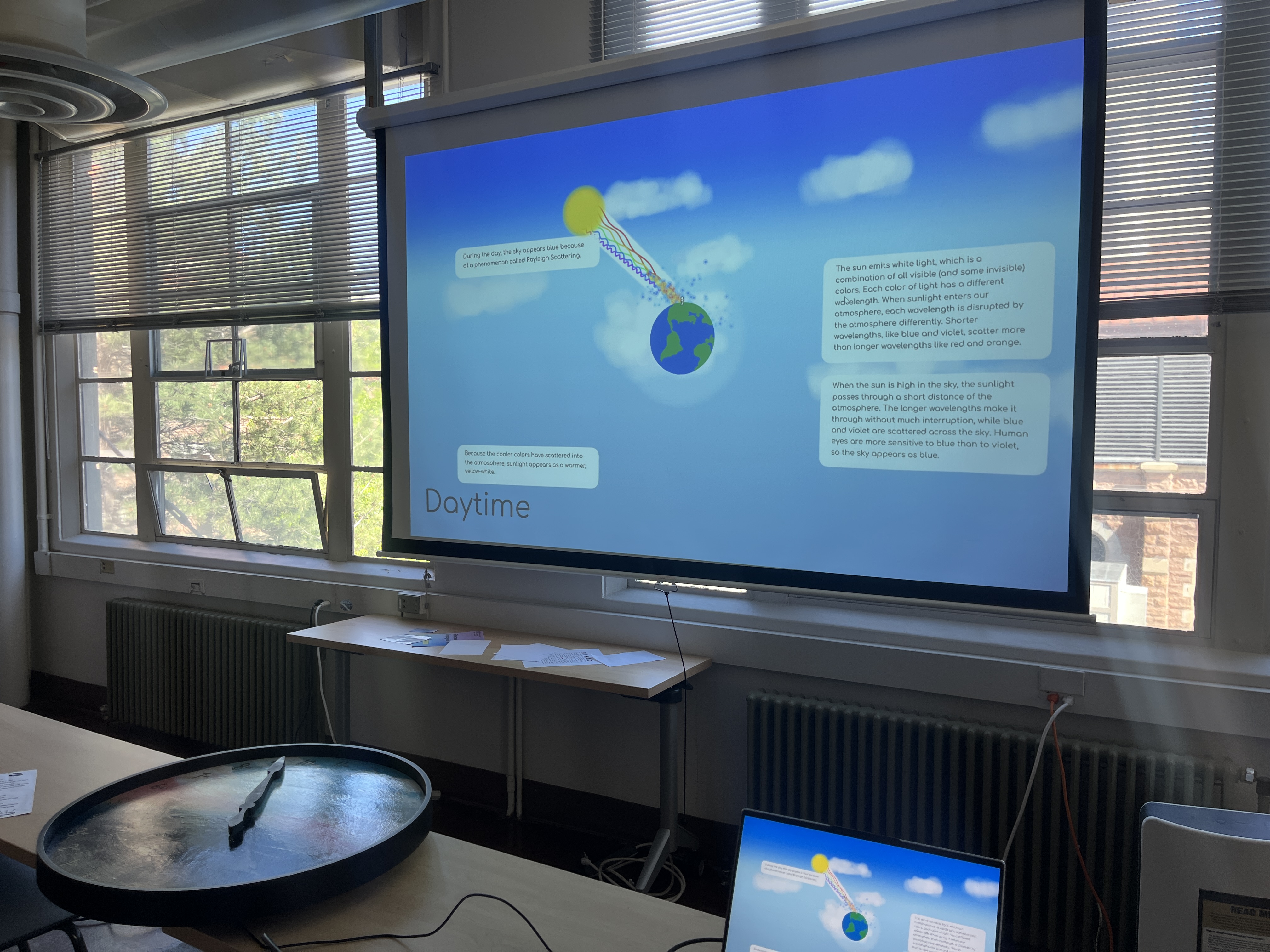 Classroom projector screen displaying a Daytime slide explaining Rayleigh scattering with sun and Earth diagram.