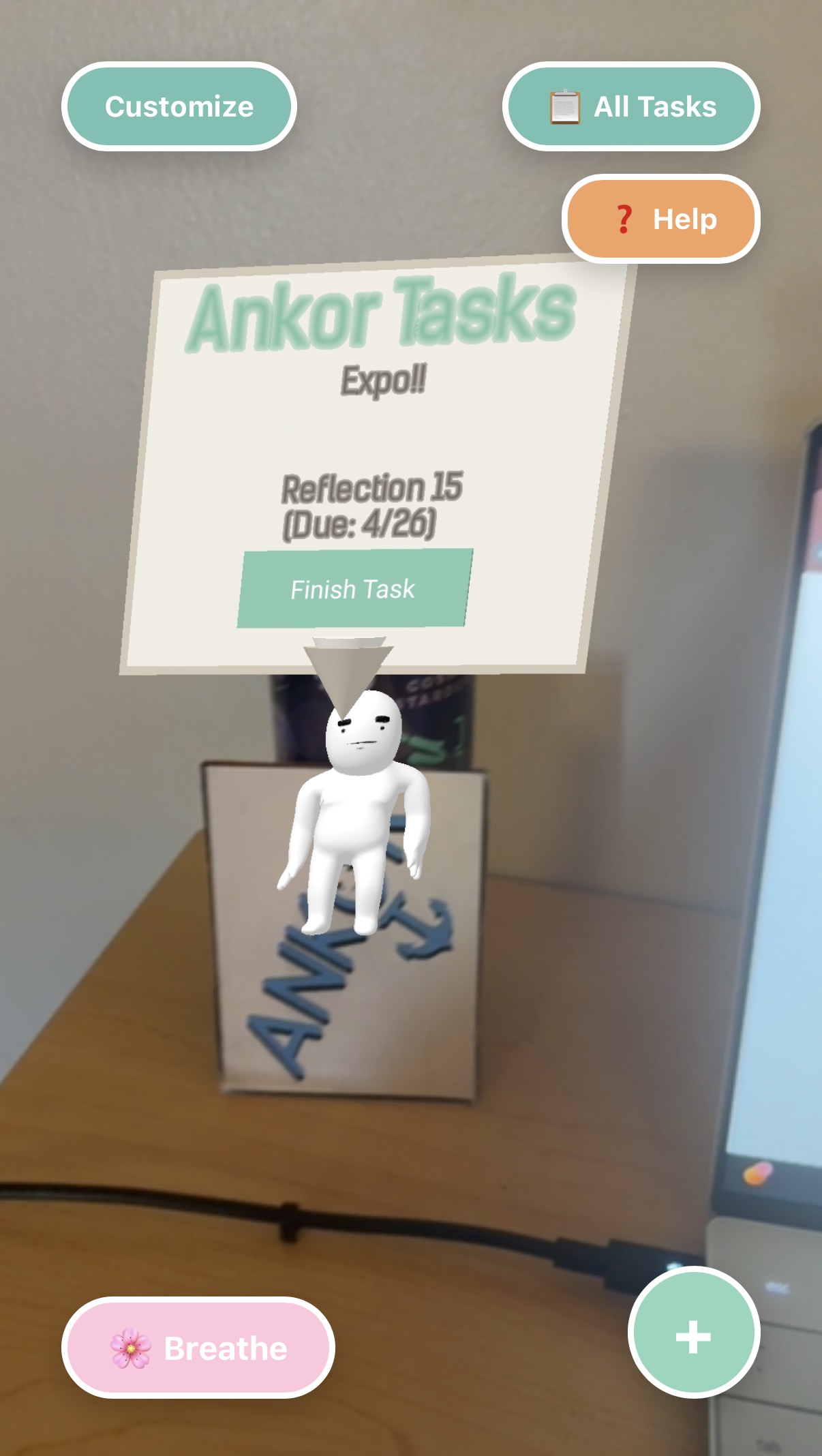 AR view of a cardboard Ankor box on a desk with the white mascot and a floating task card above it.
