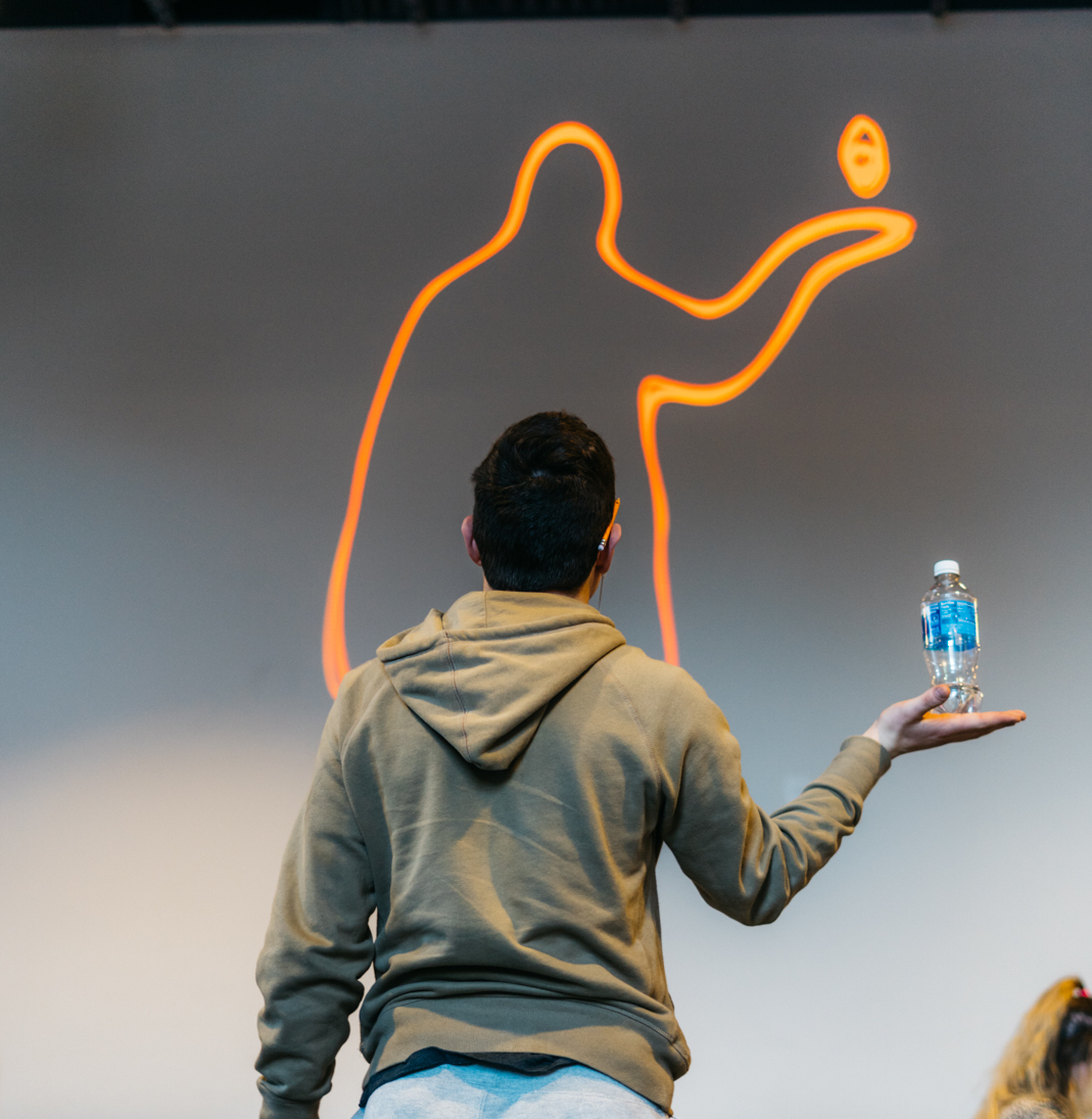 A person holding a water bottle as the screen traces their silhouette in a single glowing orange outline.