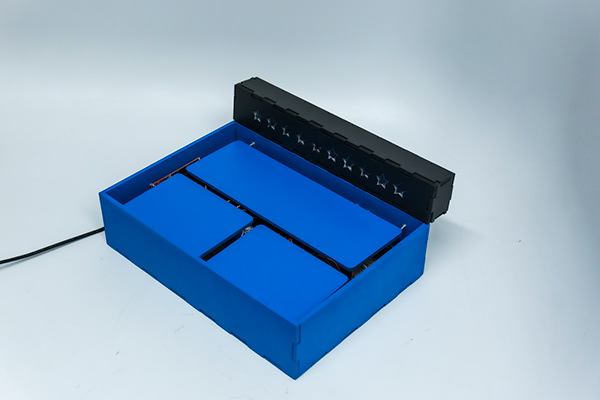 A blue laser-cut tray divided into sections with a black star-studded LED bar behind it.
