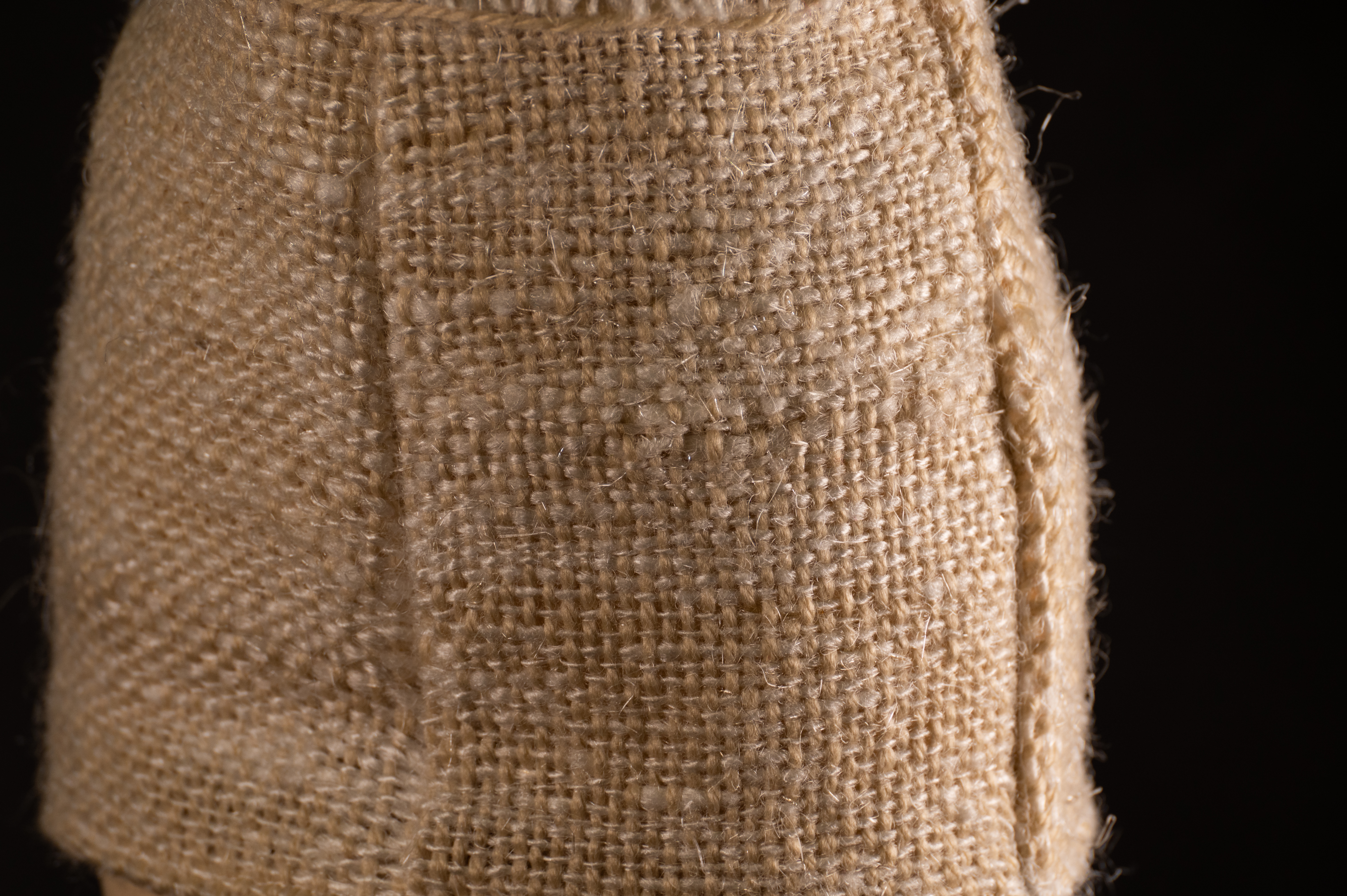 Macro close-up of the loosely woven cream fabric showing its coarse plastic-fiber weave.