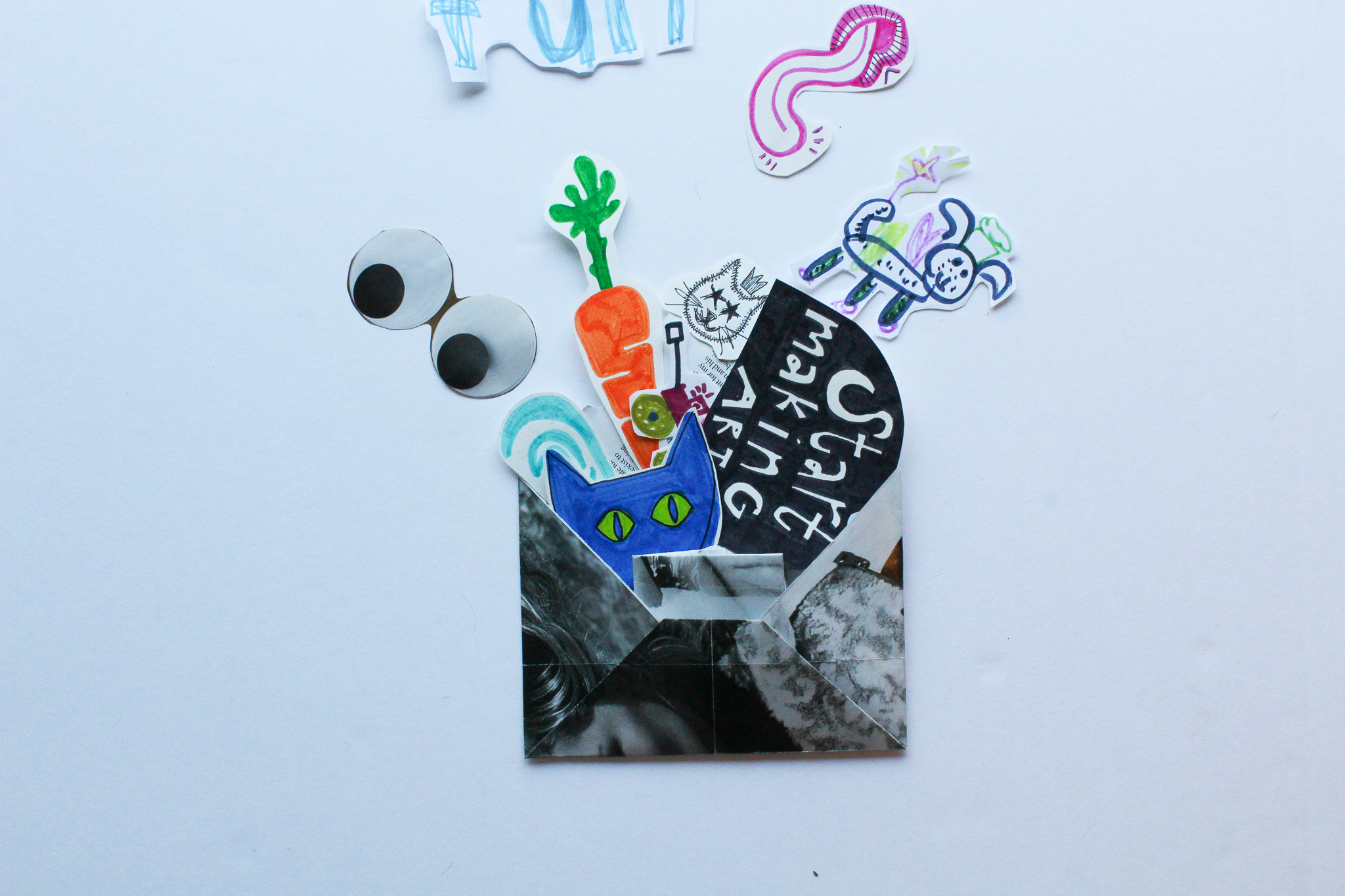 Paper envelope spilling childlike doodles of a blue cat, carrot, and a Start making art sign.