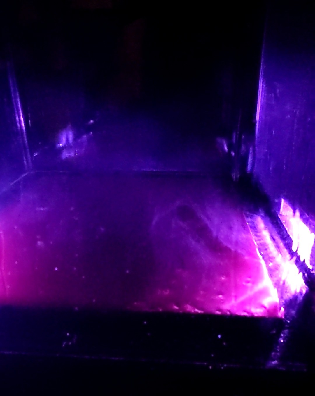 Inside the cloud chamber glowing pink and purple, with wispy vapor trails left by passing particles.