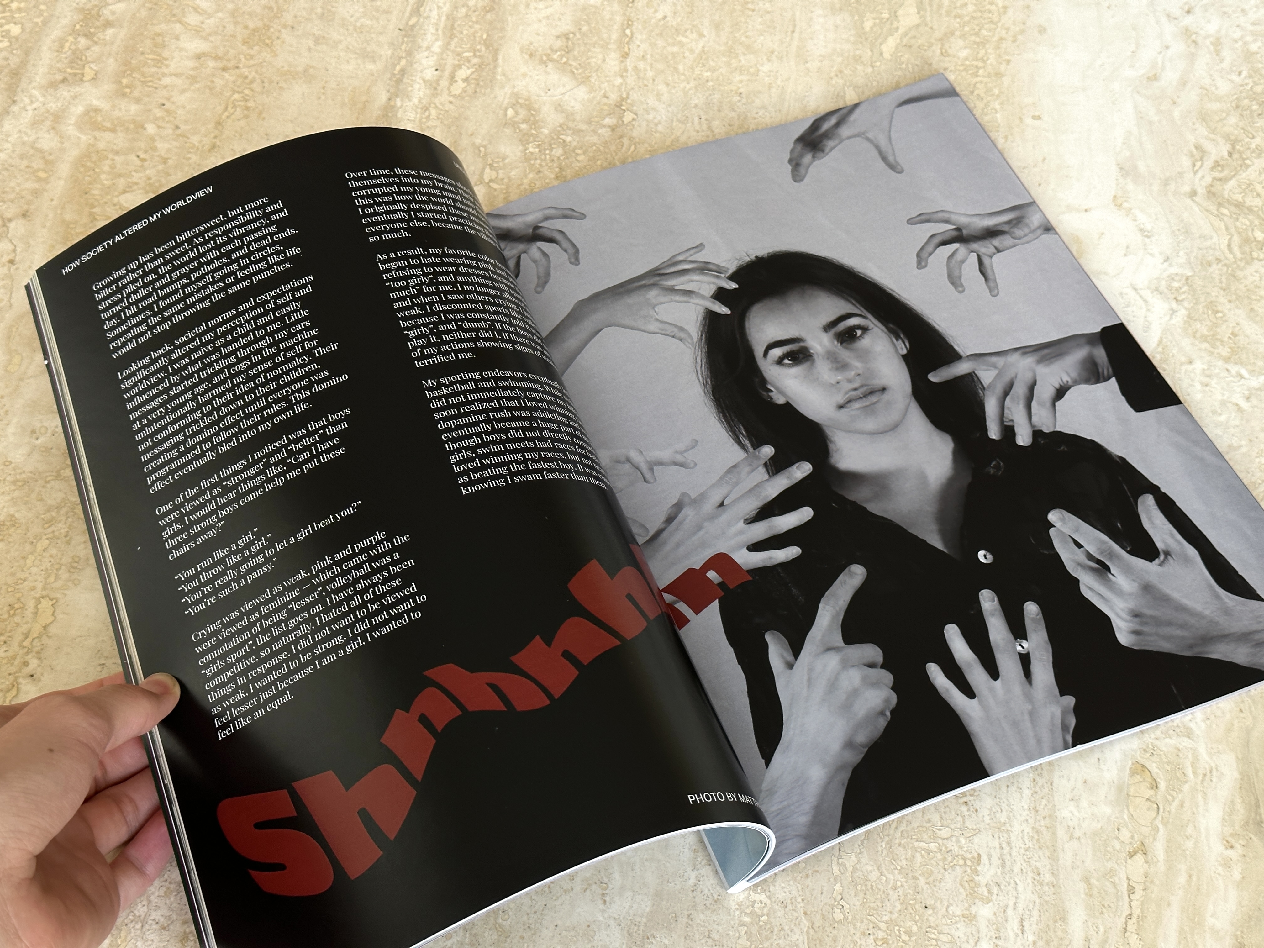 Open magazine spread: black-and-white portrait of a woman framed by many reaching hands.