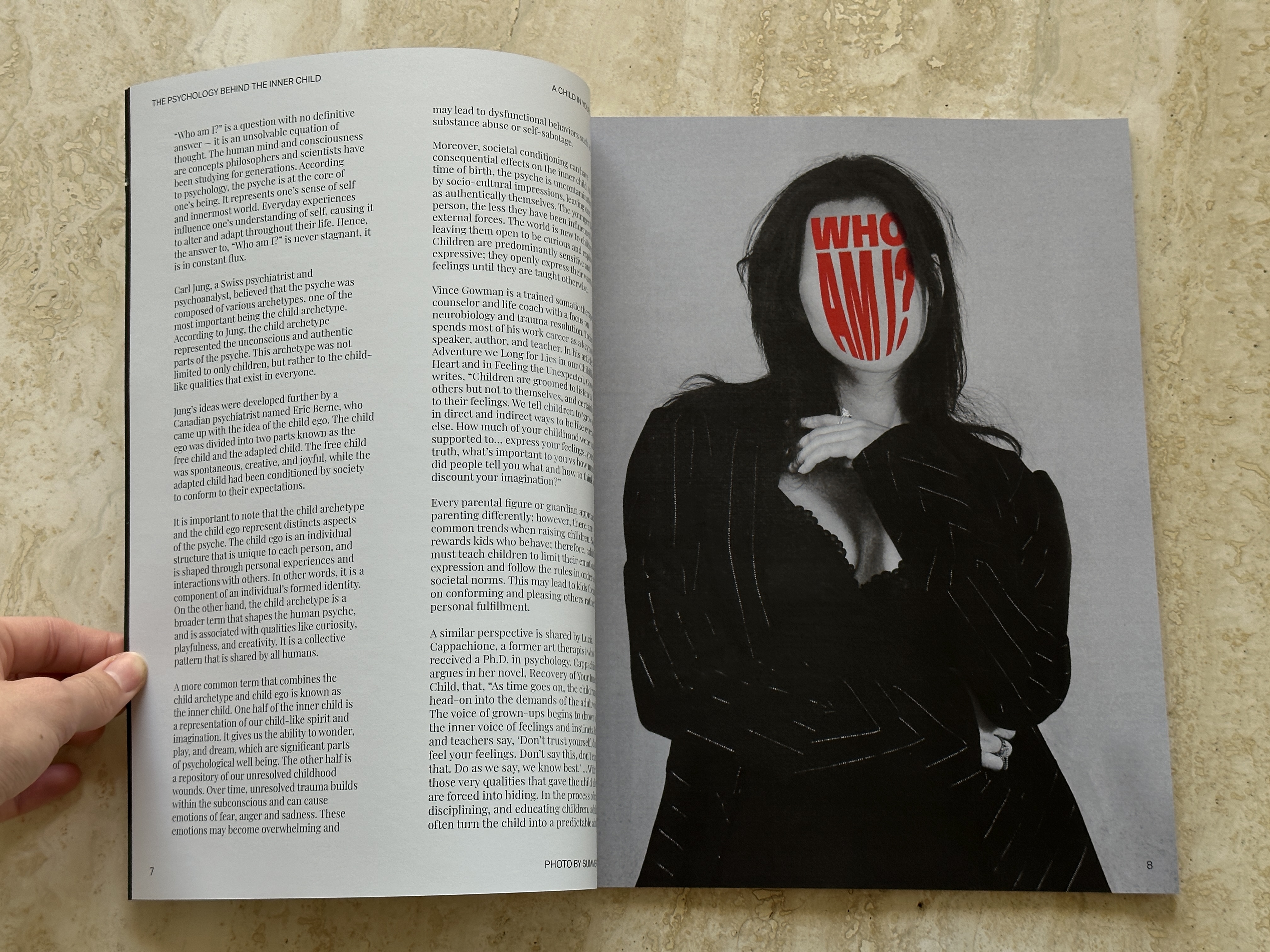 Magazine spread with a woman in black, face hidden by red 'Who Am I?' lettering.