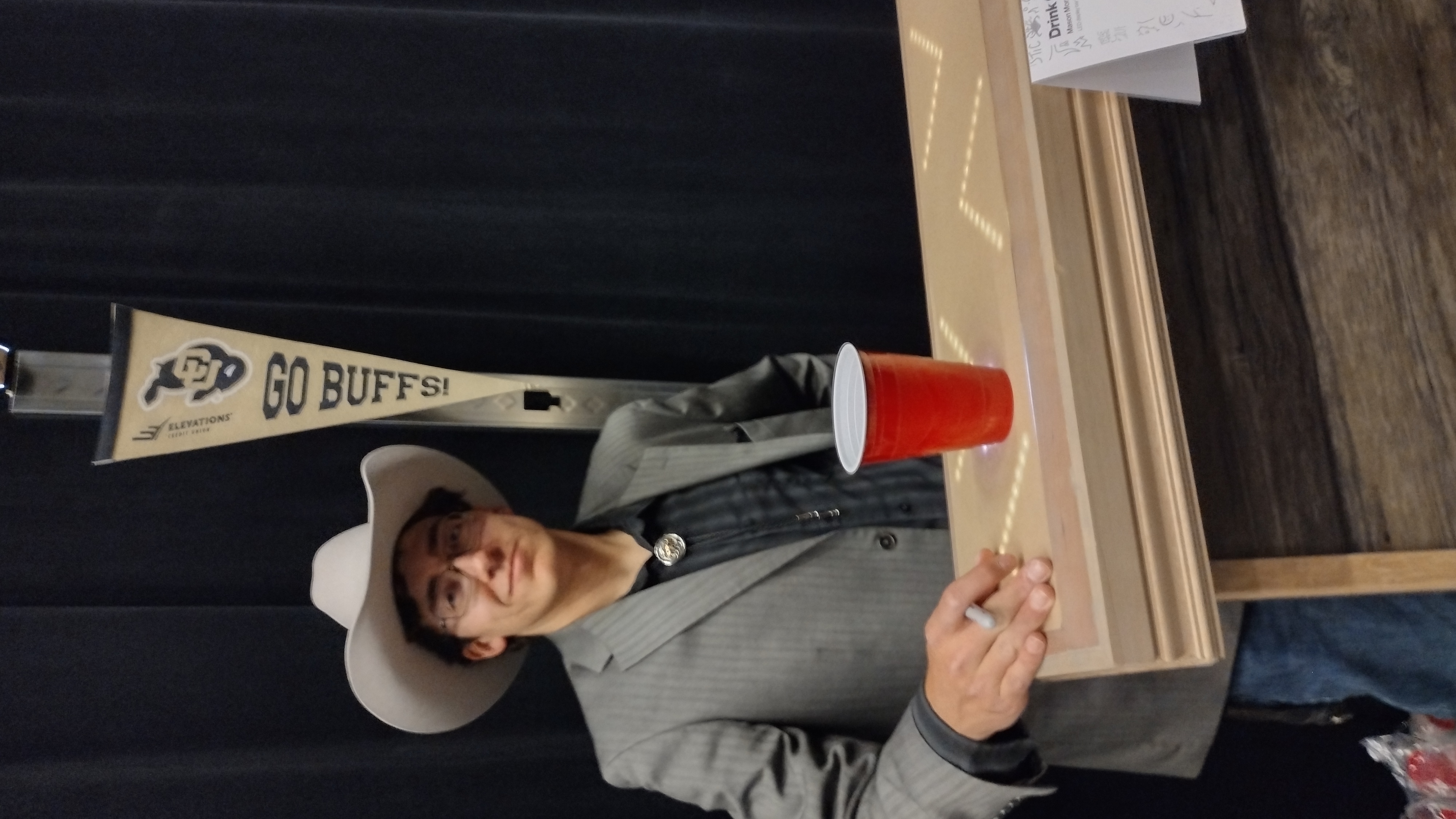A student in a cowboy hat and blazer presents the LED bar top holding a red cup.