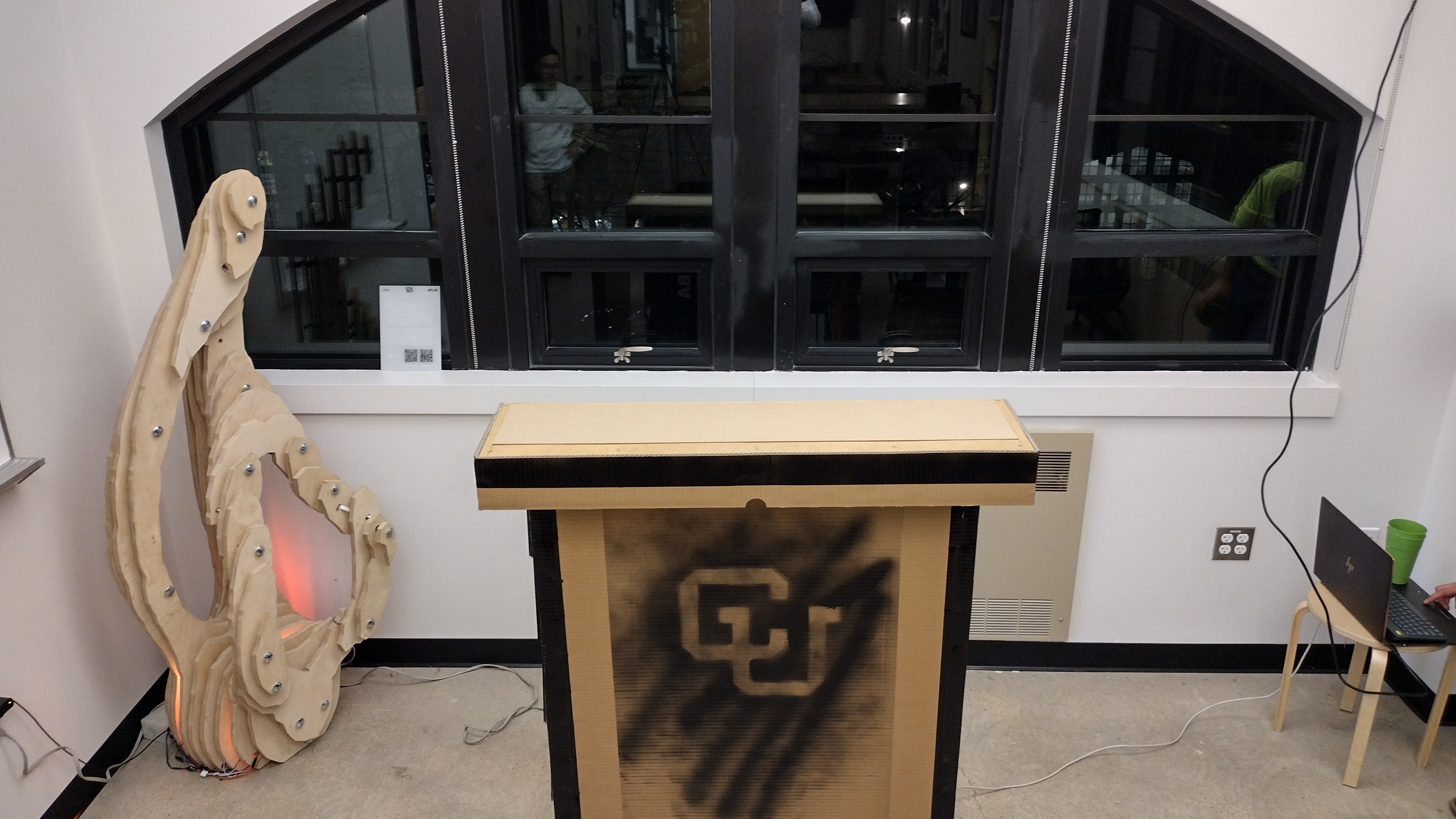 Standing bar unit with a CU-branded front panel and a carved wooden side piece indoors.