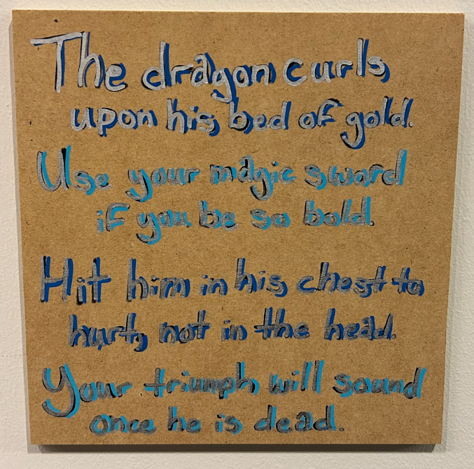 Wooden plaque with a blue rhyme about striking the dragon's chest with the magic sword to win.