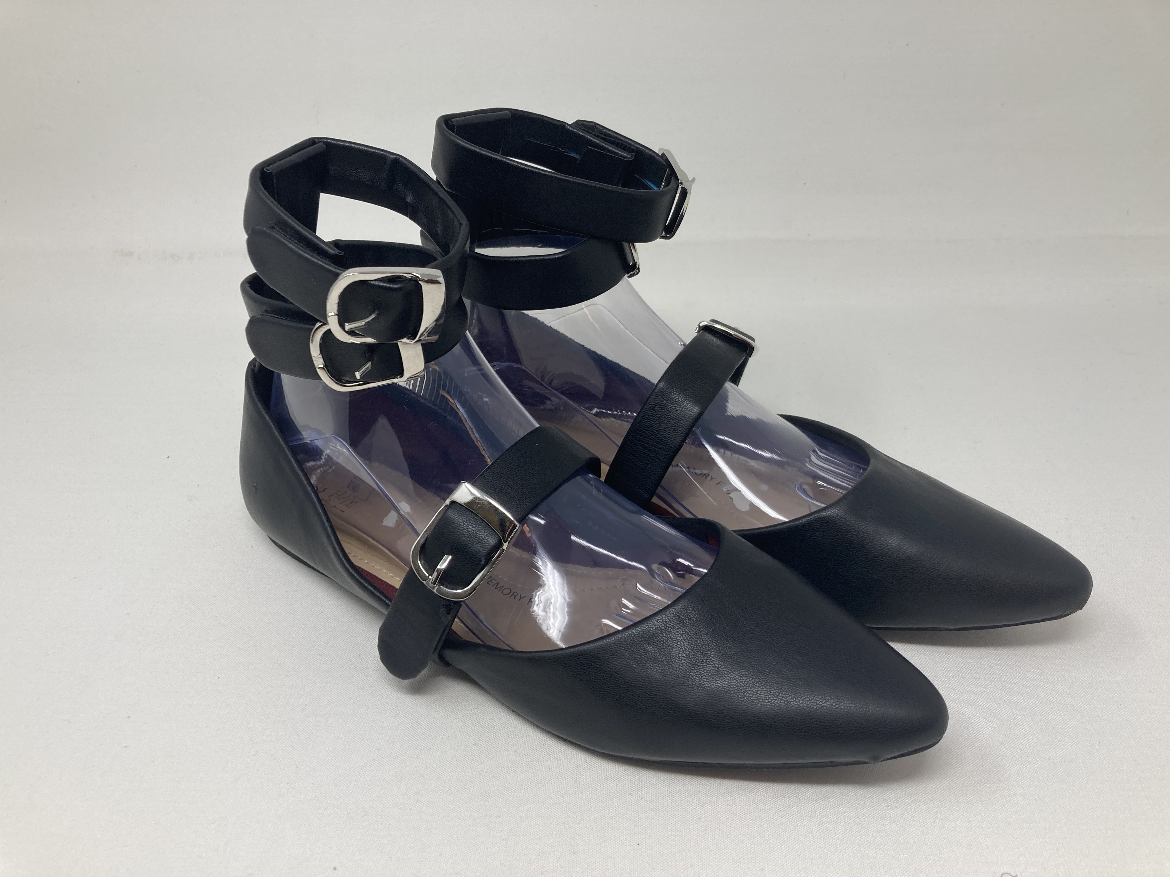 Black pointed-toe flats with double ankle straps and a buckled strap across the foot.