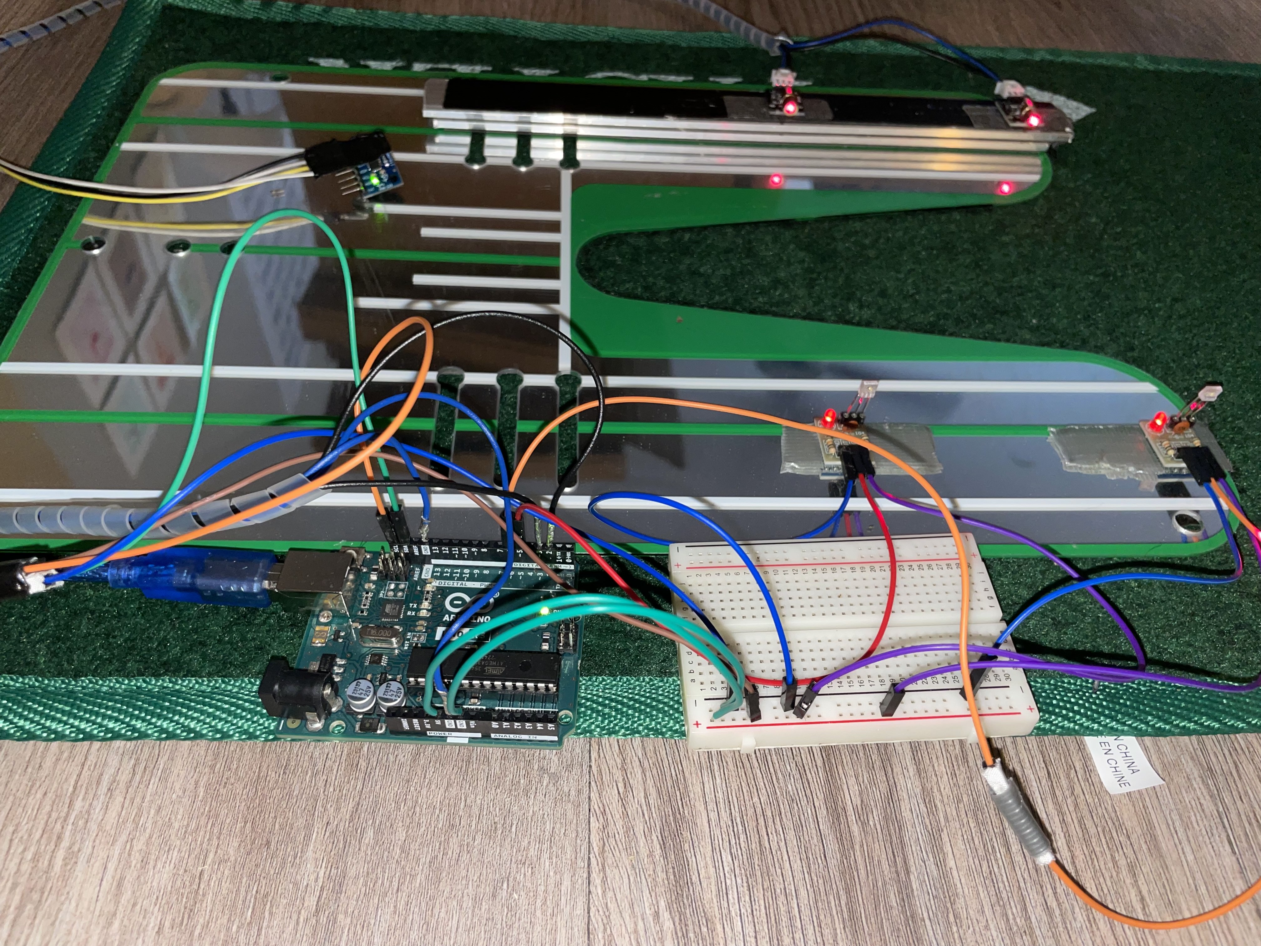 DIY putting mat wired to an Arduino and breadboard with red sensor LEDs along the lanes.