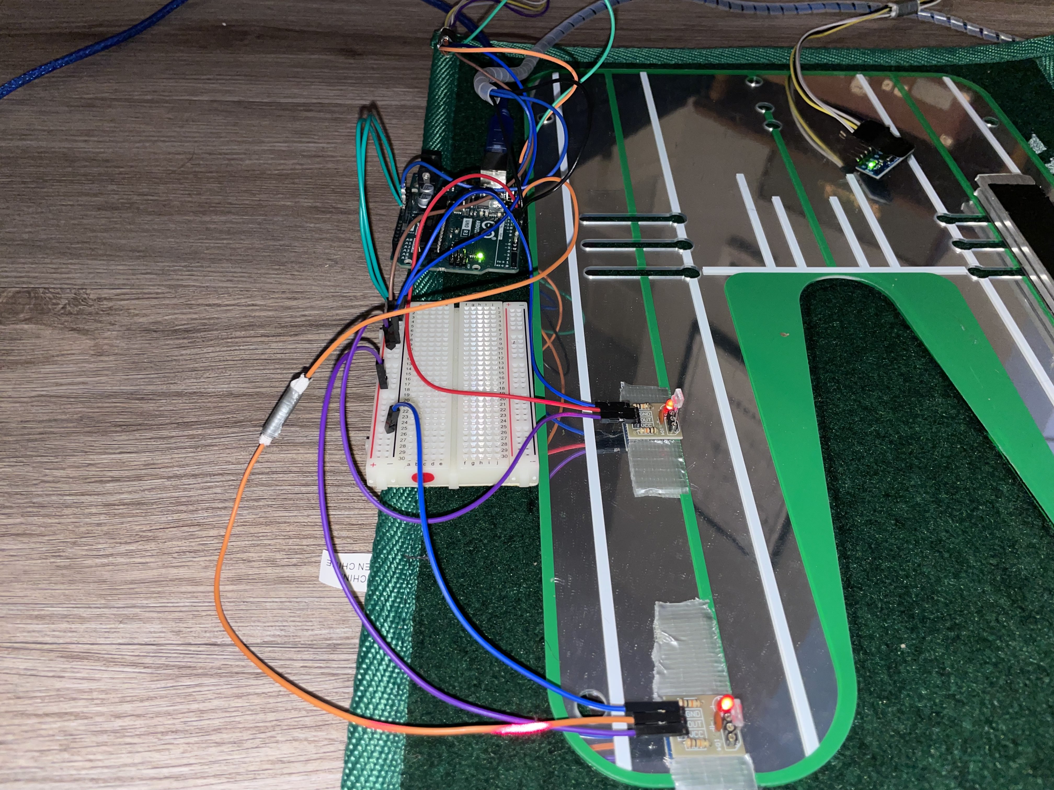 Putting-green prototype on the floor with an Arduino, breadboard, and tangled jumper wires.