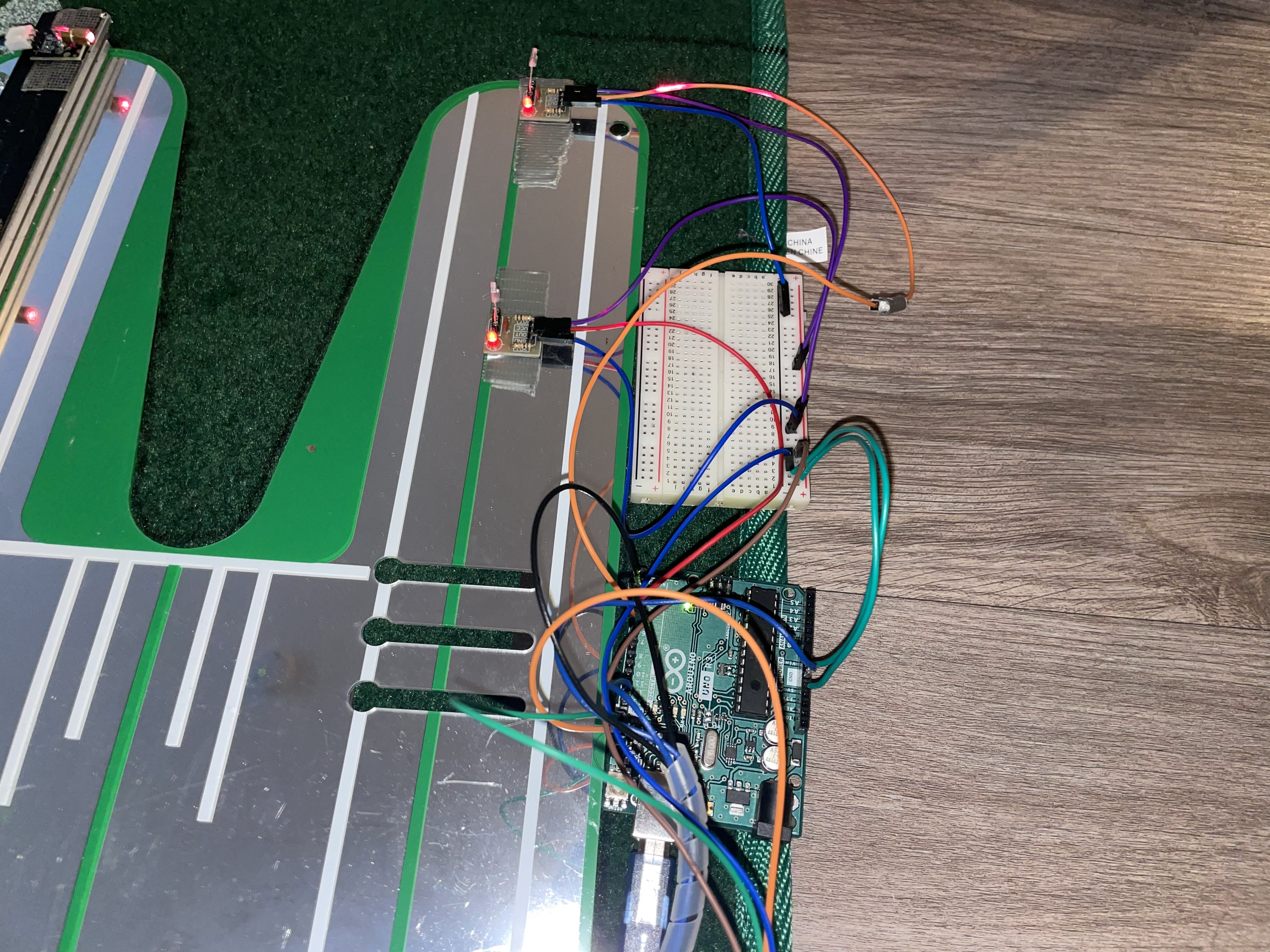 Side view of the sensor-wired putting mat with breadboard and Arduino on a wood floor.