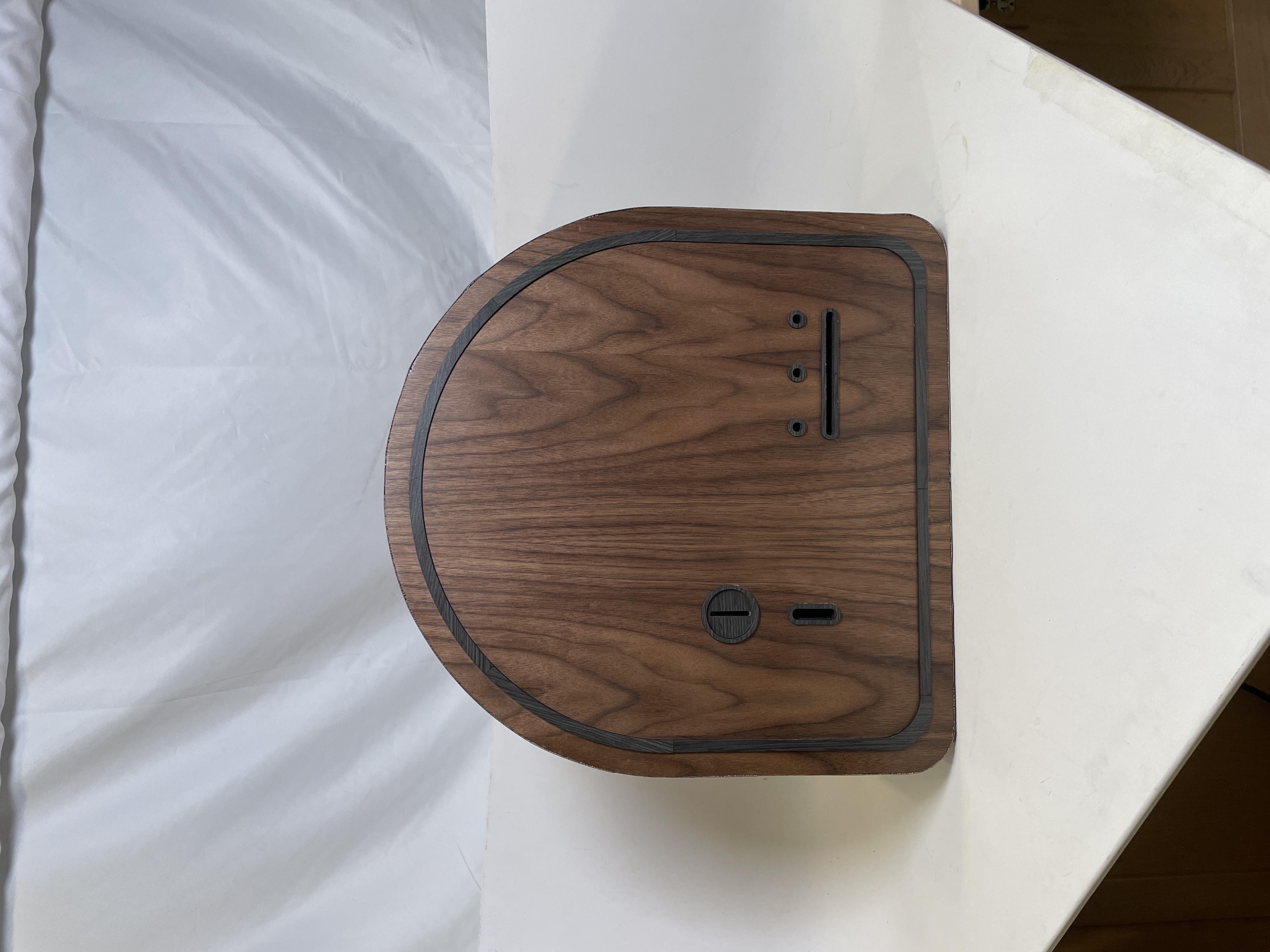 The closed arched wooden machine front with a knob, coin slot, and a sticker dispensing slot.
