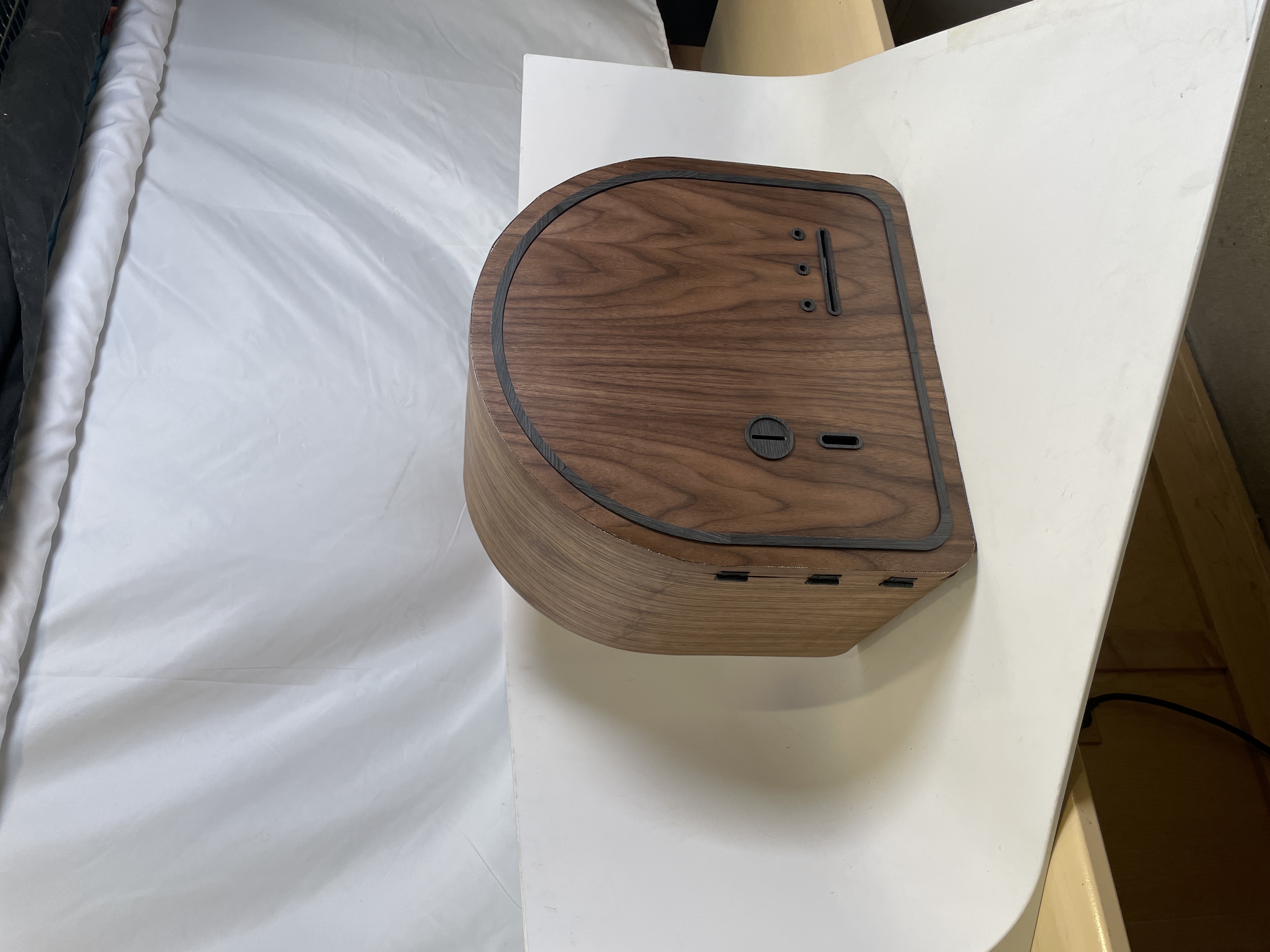 Three-quarter view of the assembled arched walnut sticker machine on a white surface.