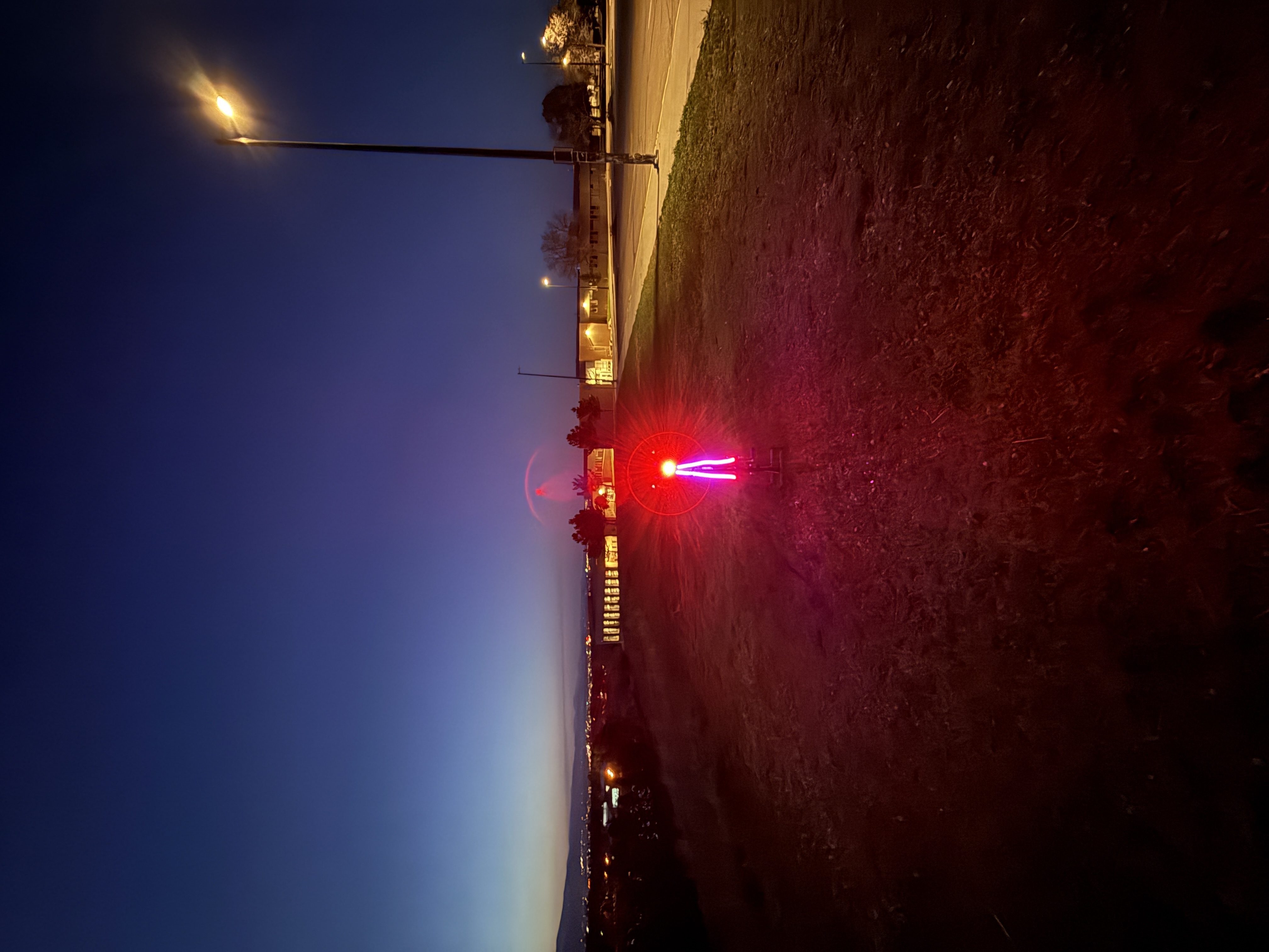 Cyclist at dusk seen head-on, bike wheel ringed with bright red LED light.