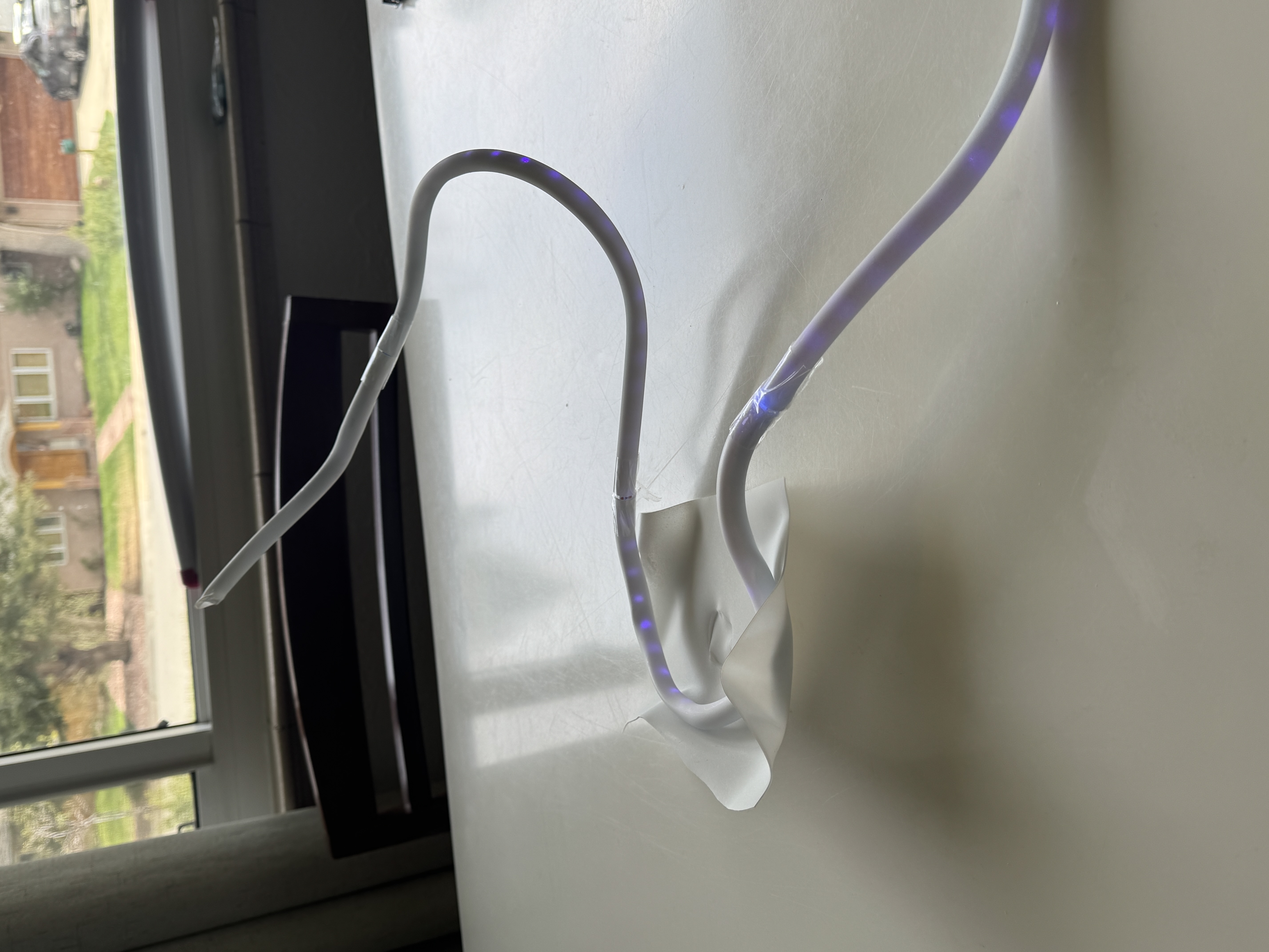 A clear curving acrylic tube sculpture with embedded blue LEDs winding across a white table.