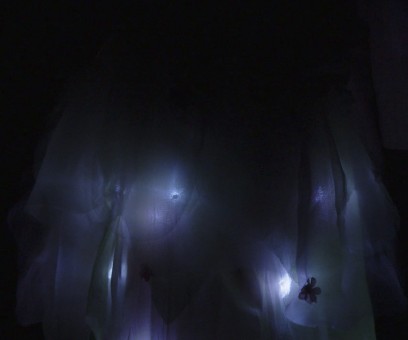 The illuminated gown skirt in near-darkness, white LEDs glowing through layers of tulle.