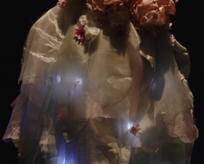 Close-up of the gown's sheer LED-lit skirt, flowers and blue lights glowing through the fabric.