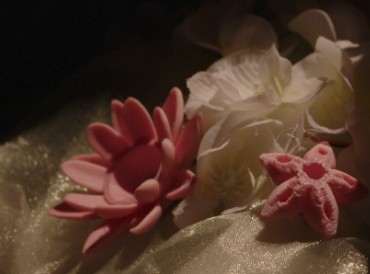 Detail of a pink lotus and white flowers resting on shimmering fabric of the installation.