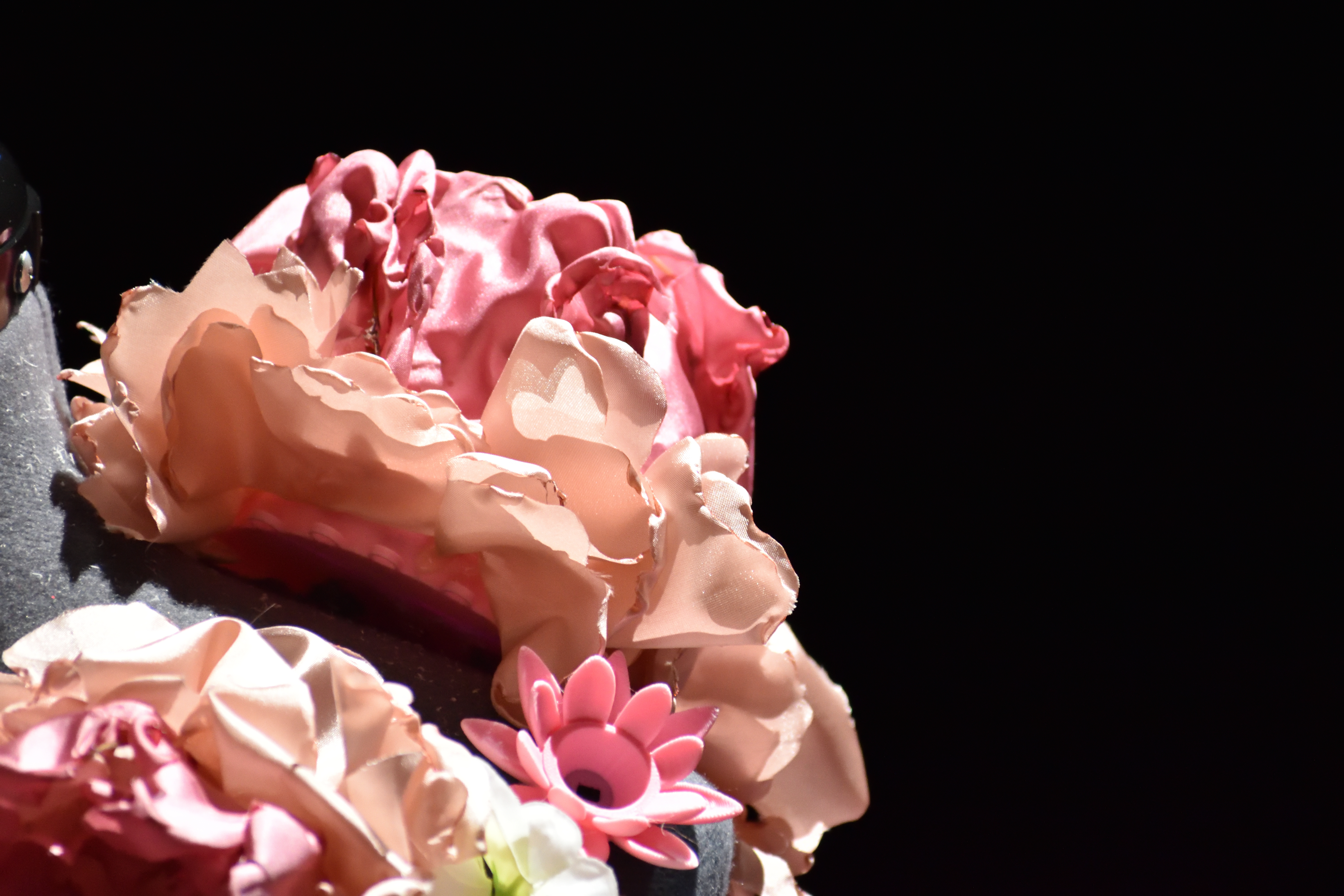 Close-up of ruffled peach and pink fabric flowers with a small pink lotus on the gown.
